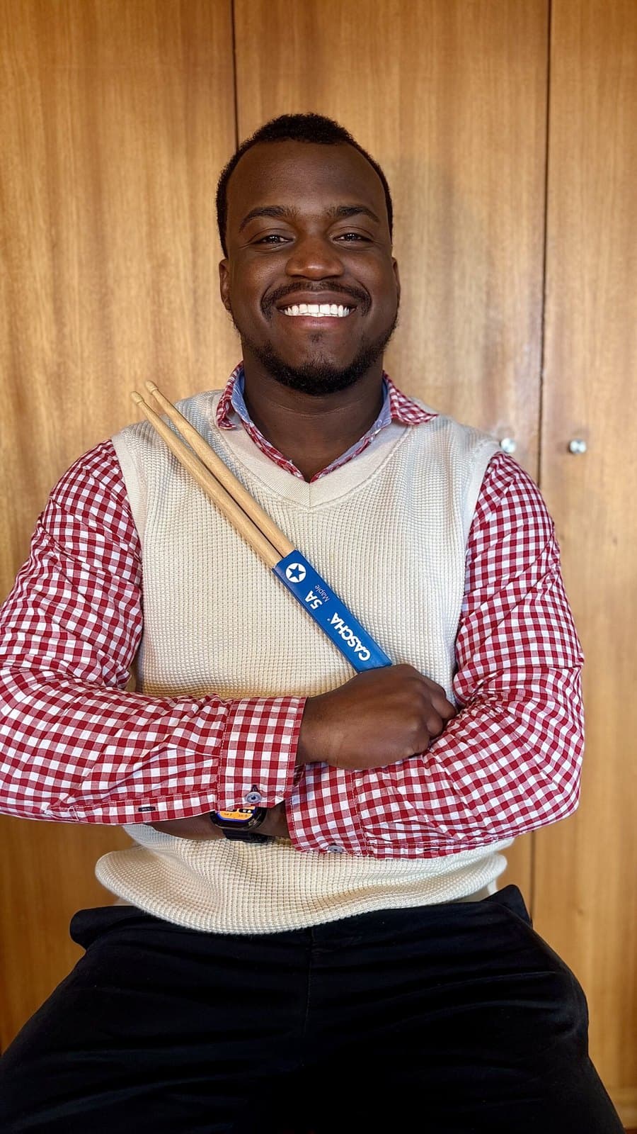 Ivirson de braços cruzados, com as baquetas Cascha 5A Maple ao ombro